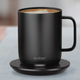 The Ember self-heating mug on its charging base sitting on a desk.